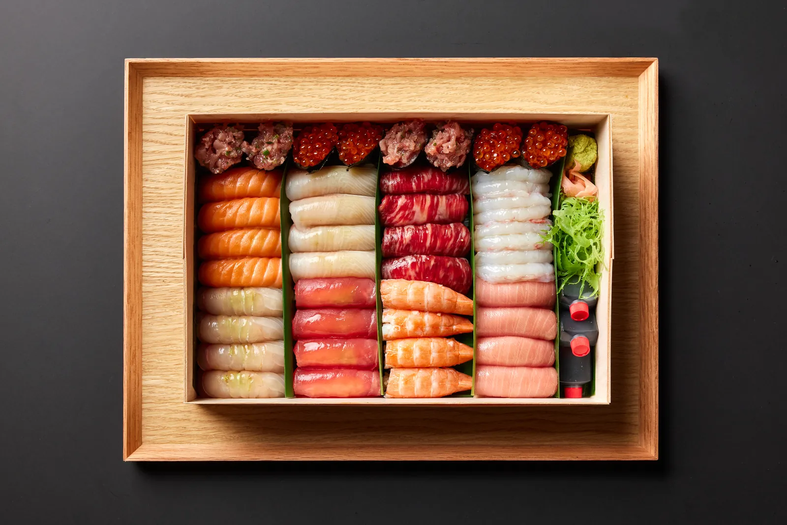 A wooden box of nigiri on a tray